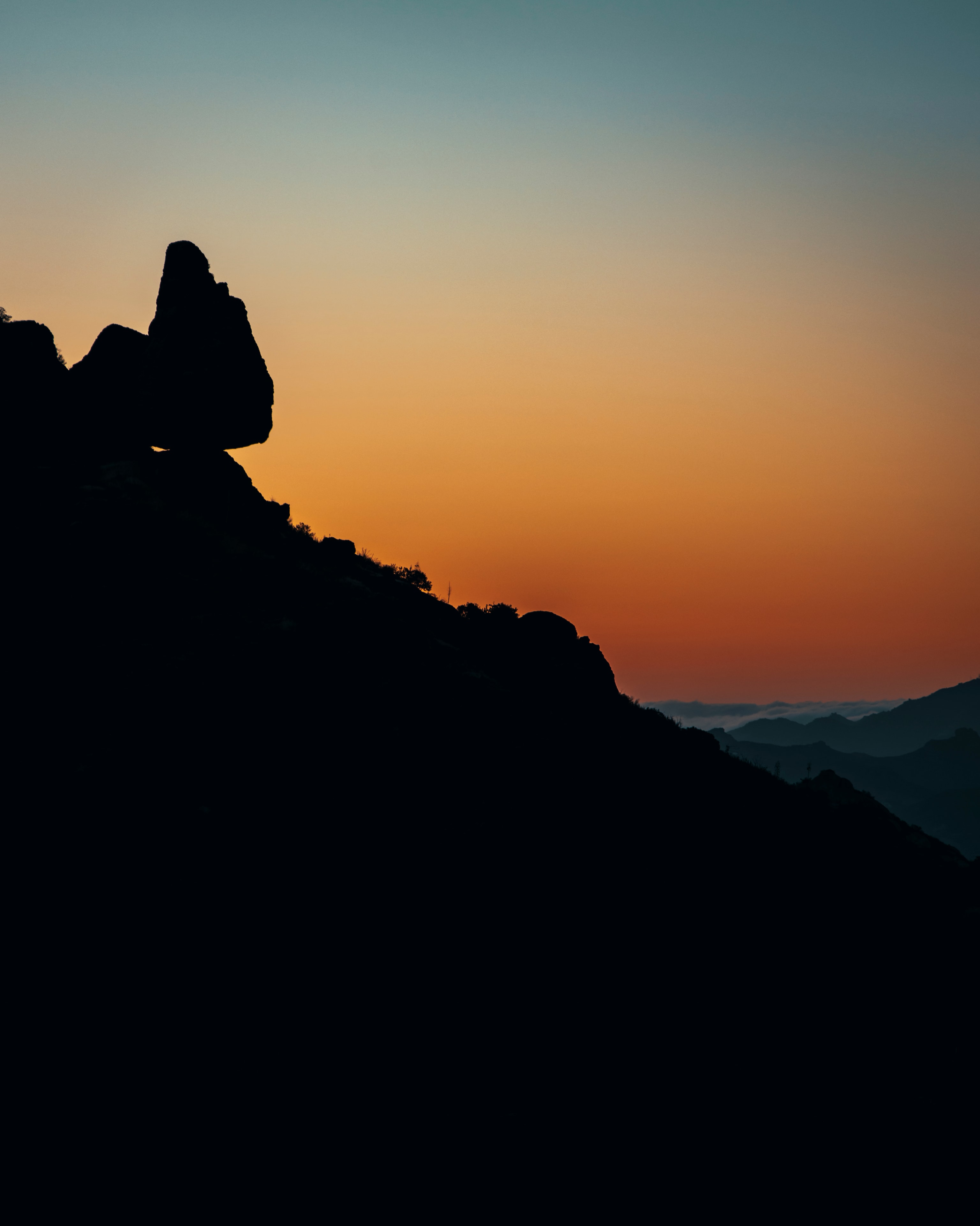 Balanced rock silhouette against fiery orange sunset sky, Mishe Mokwa Trail