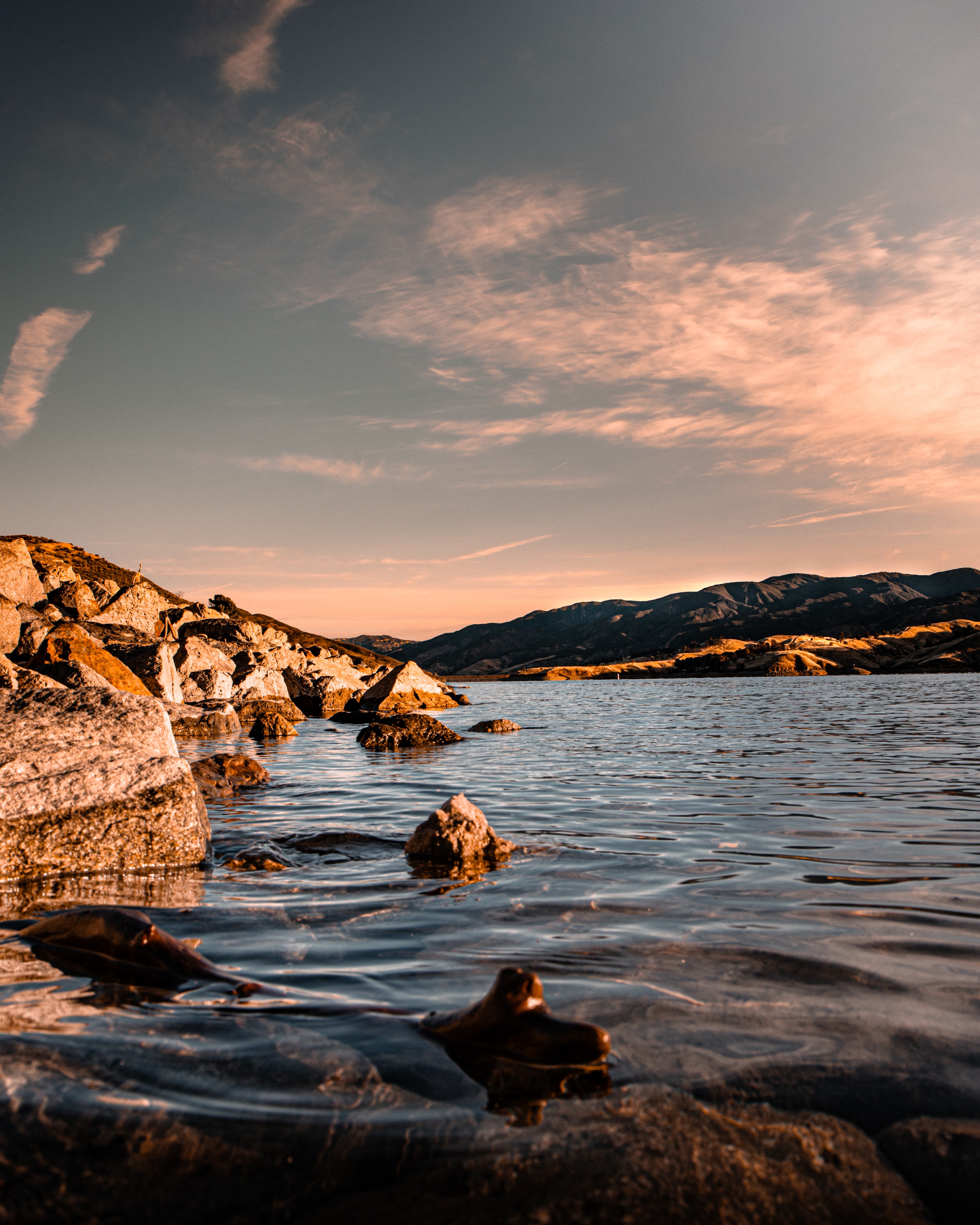 Rocky lakeshore at golden hour with mountain range