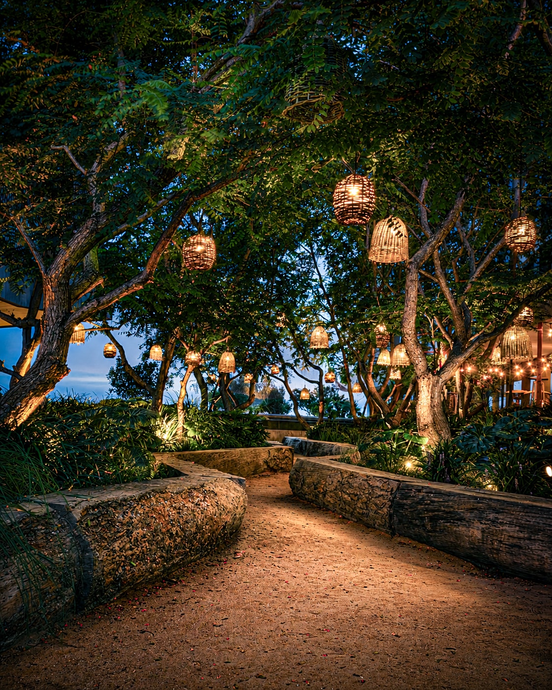 Garden path with hanging lanterns in trees at dusk