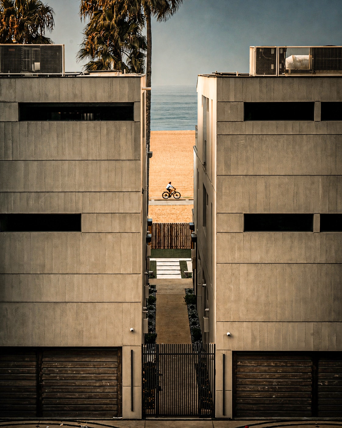 Beachfront buildings framing cyclist on sand