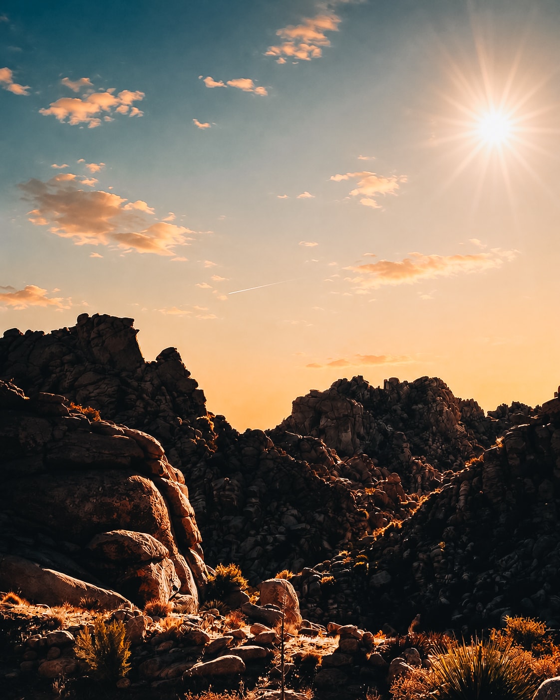 Desert rock formations with starburst sun at golden hour