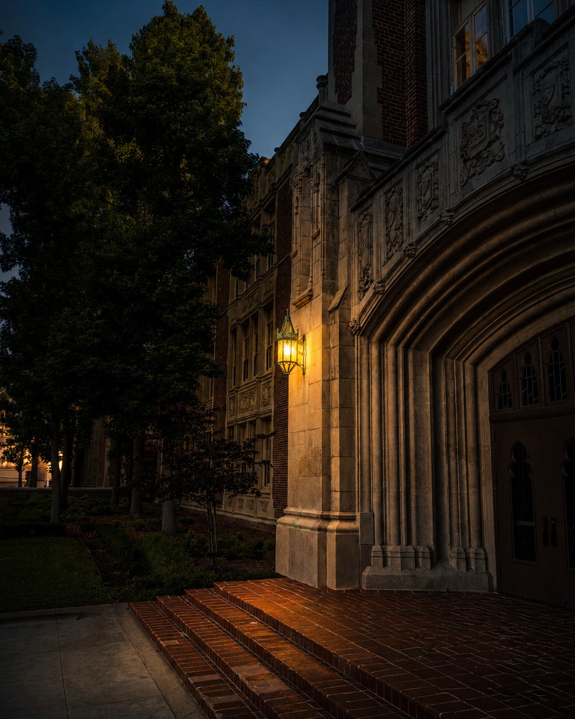 Gothic university building illuminated by lantern at dusk