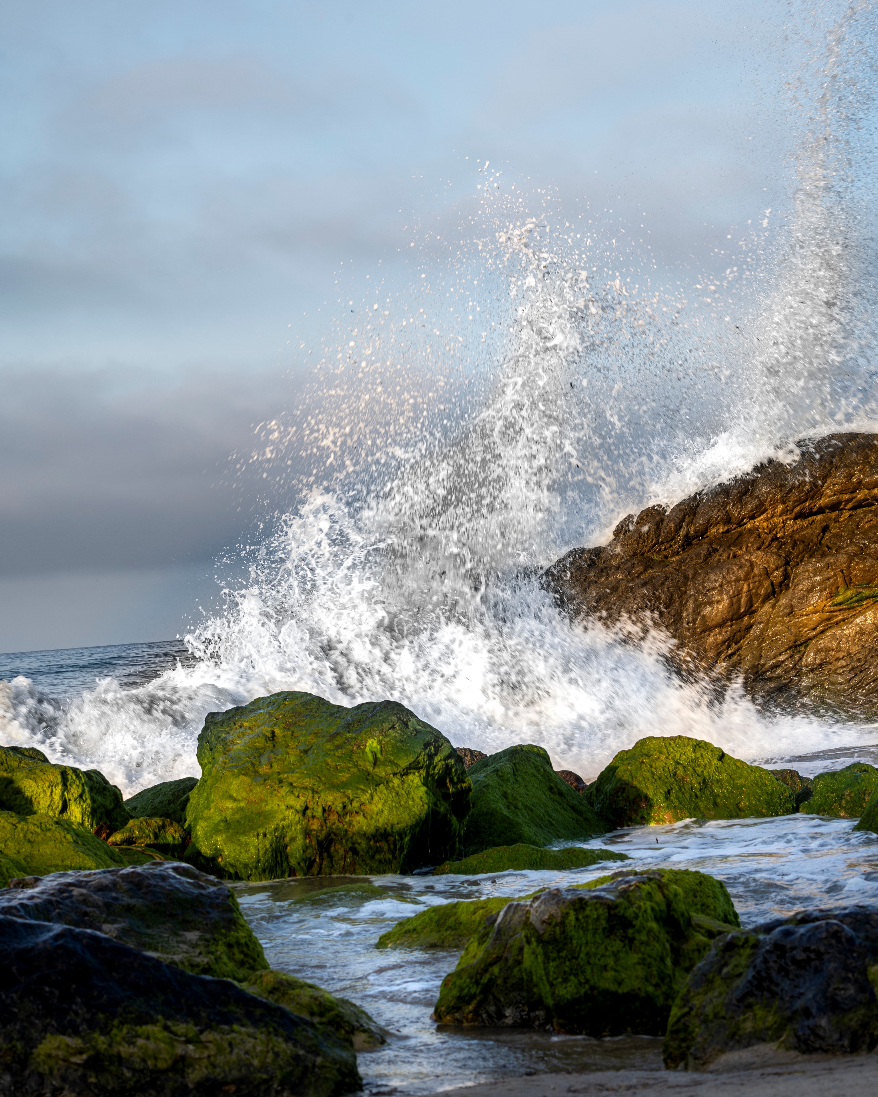Waves crashing on moss-covered rocks