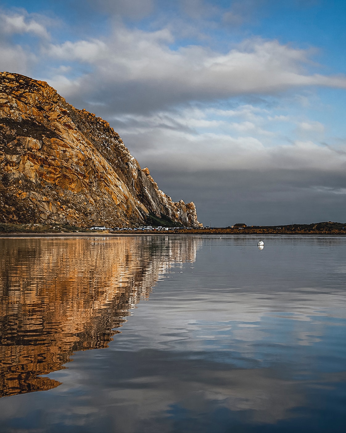 Rocky cliff reflecting calm coastal waters